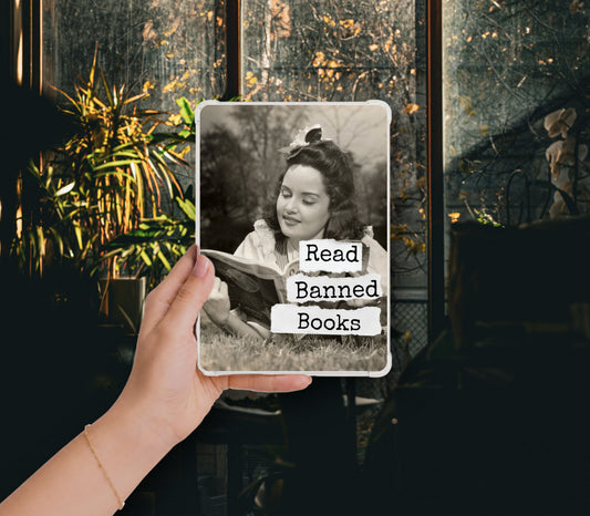 Read Banned Books printable Kindle clear case insert featuring a vintage woman reading outdoors with a curious bird perched above her, shown in a clear Kindle case held against a dark botanical background.
