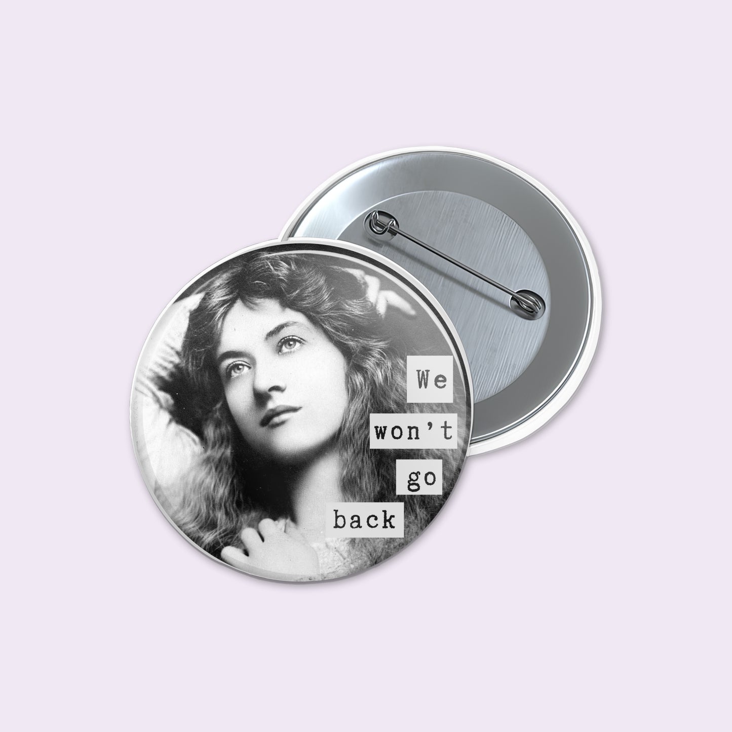 Round pinback button shows a black-and-white portrait of a woman with the text 'We won't go back' in white letter blocks.