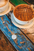Cappuccino with a lattice pattern on top, served in a white cup on a blue wooden surface, showing off an upcycled book page pendant necklace on a chippy blue wooden table - Whimsy Spirit Shop