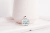 Upcycled book page pendant necklace with book page text on a white background