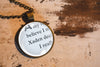 Necklace with a pendant displaying upcycled book page text on a wooden surface