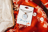 Necklace with an upcycled book page pendant on a branded card on a red fabric background
