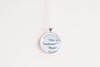 Round silver-toned upcycled book page pendant necklace with text on a white background