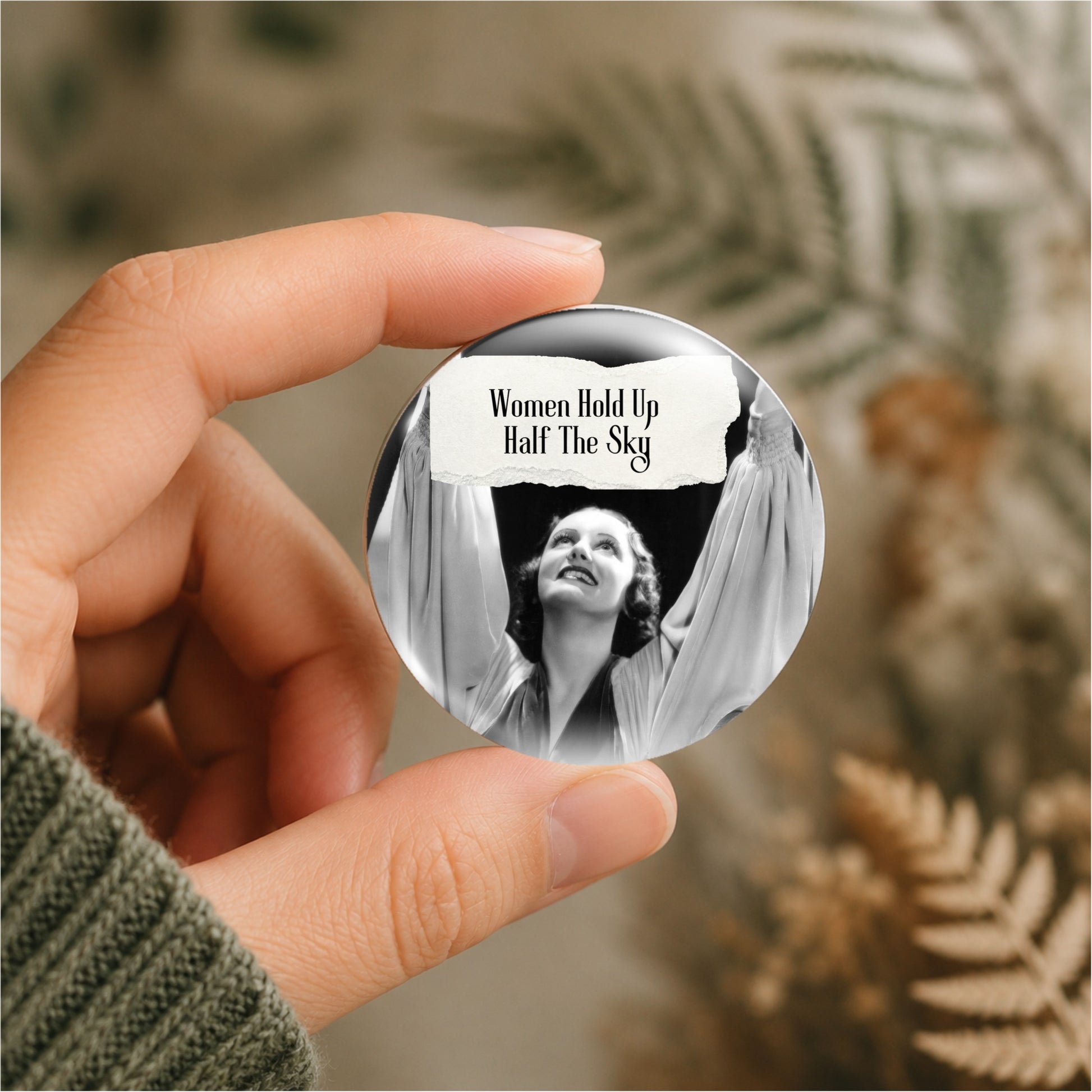 Feral retro woman pin back button with quote that says "Women Hold Up Half The Sky" shown being held