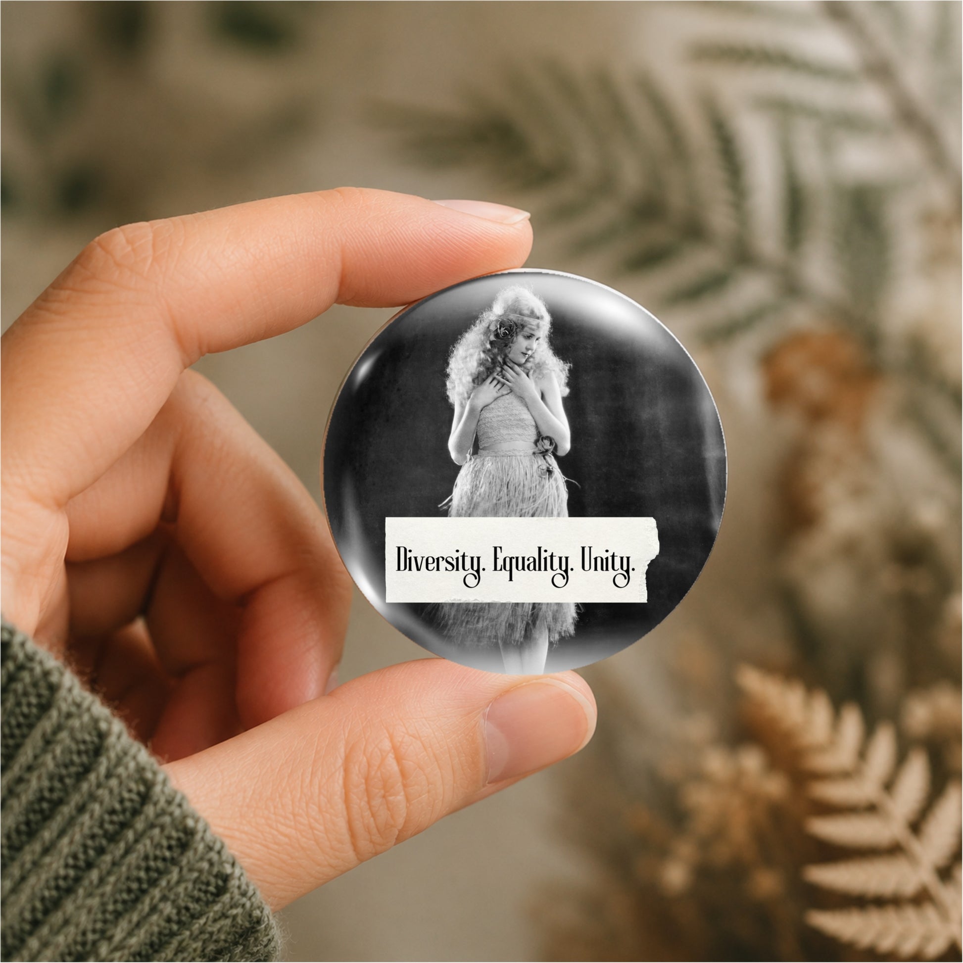 Retro woman on a pin back button with writing "Diversity. Equality. Unity." shown being held