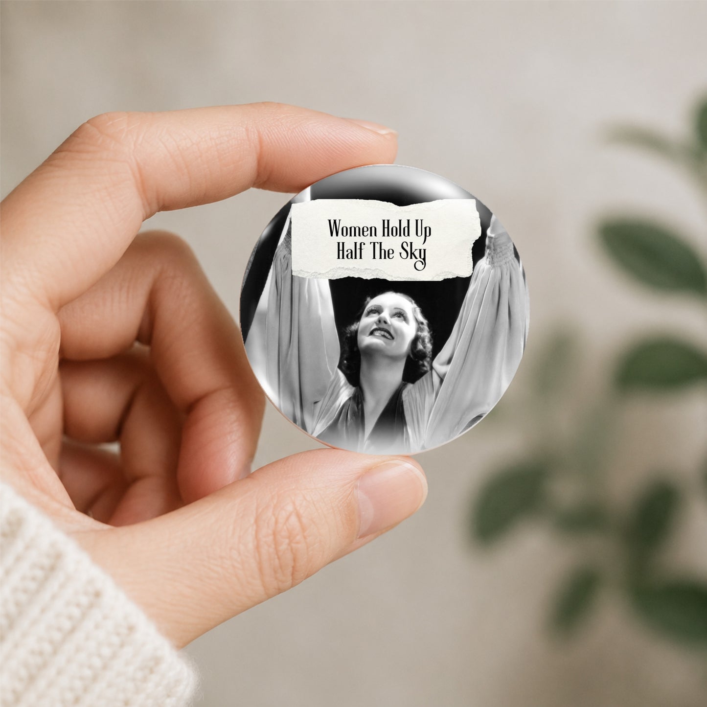 Feral retro woman pin back button with quote that says "Women Hold Up Half The Sky" shown being held