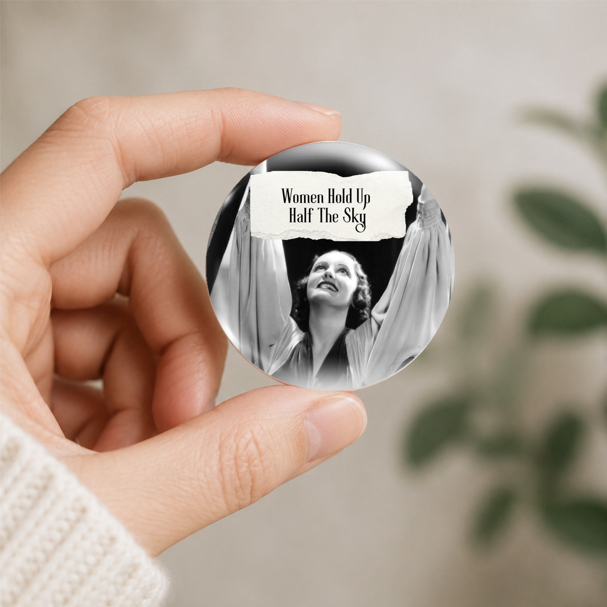 Feral retro woman pin back button with quote that says "Women Hold Up Half The Sky" shown being held
