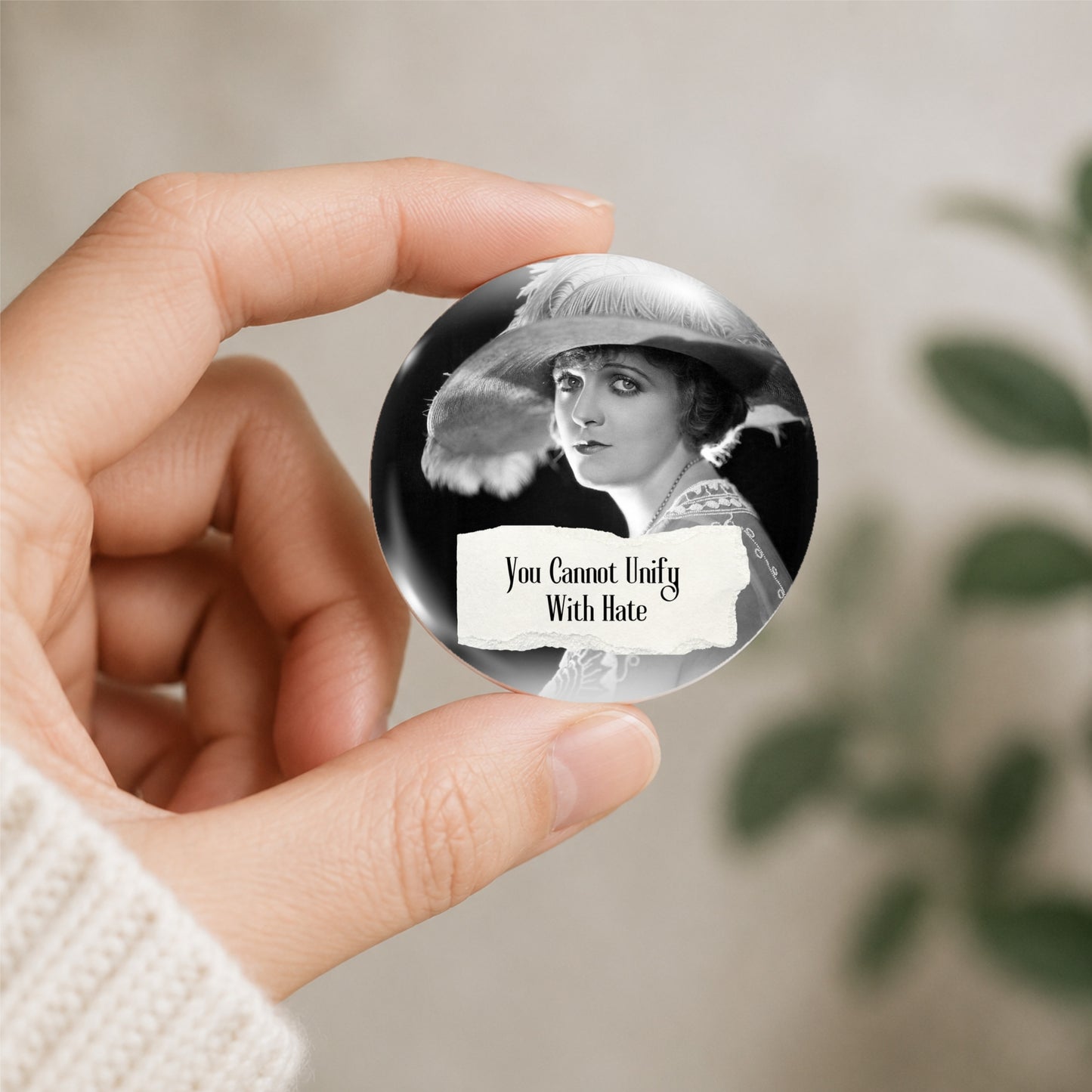 Pinback button shown being held featuring a retro woman and the quote "You Cannot Unify With Hate"