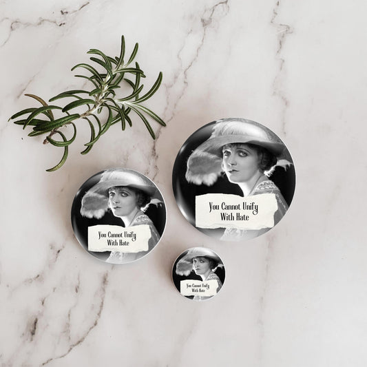 Pinback button shown representing three sizes and featuring a retro woman and the quote "You Cannot Unify With Hate"