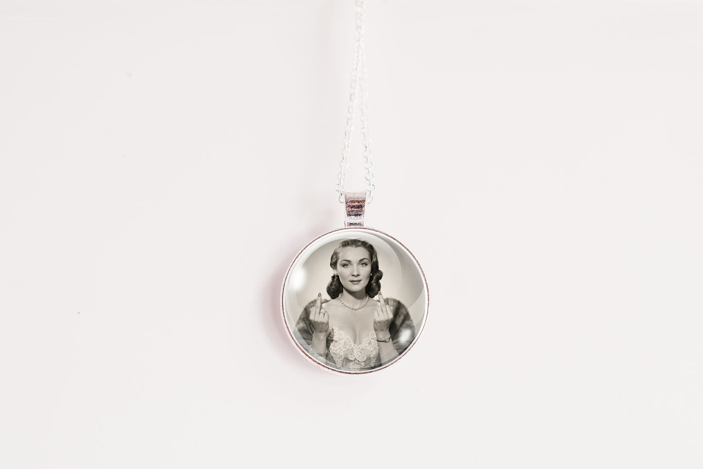 A silver circular pendant necklace featuring a black-and-white portrait photo of a woman, suspended from a white cord against a plain white background.