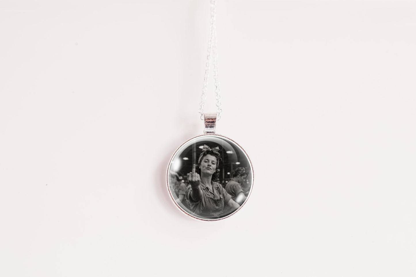 A silver circular pendant necklace featuring a black and white portrait photo of a woman, suspended from a thin white chain against a plain white background.