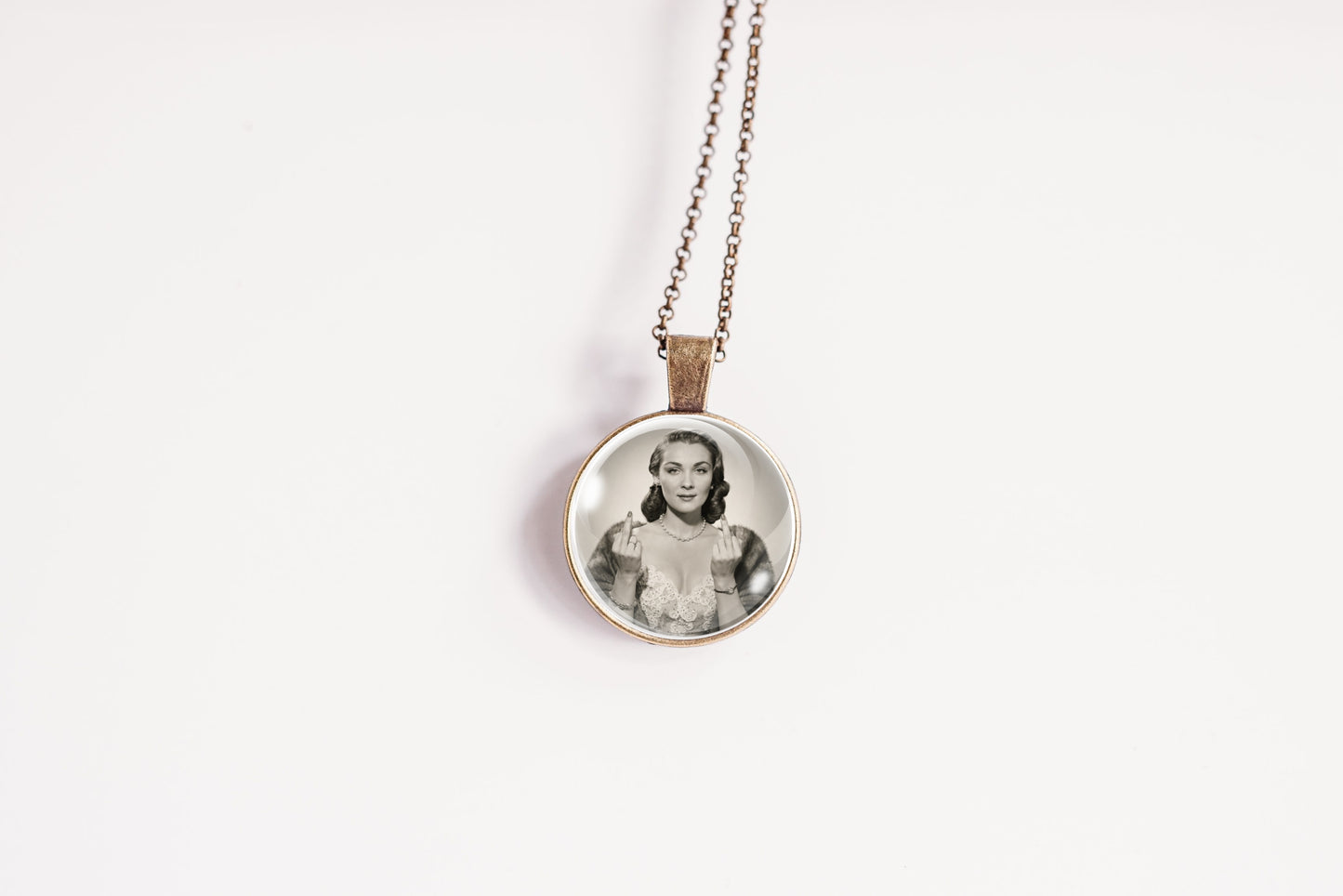 A round pendant necklace featuring a black and white portrait photograph of a woman, suspended from a delicate bronze-toned chain against a plain white background.