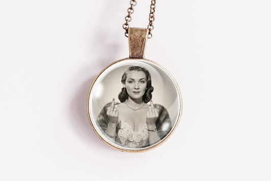 A round pendant necklace featuring a black and white portrait photograph of a woman, suspended from a delicate bronze-toned chain against a plain white background.