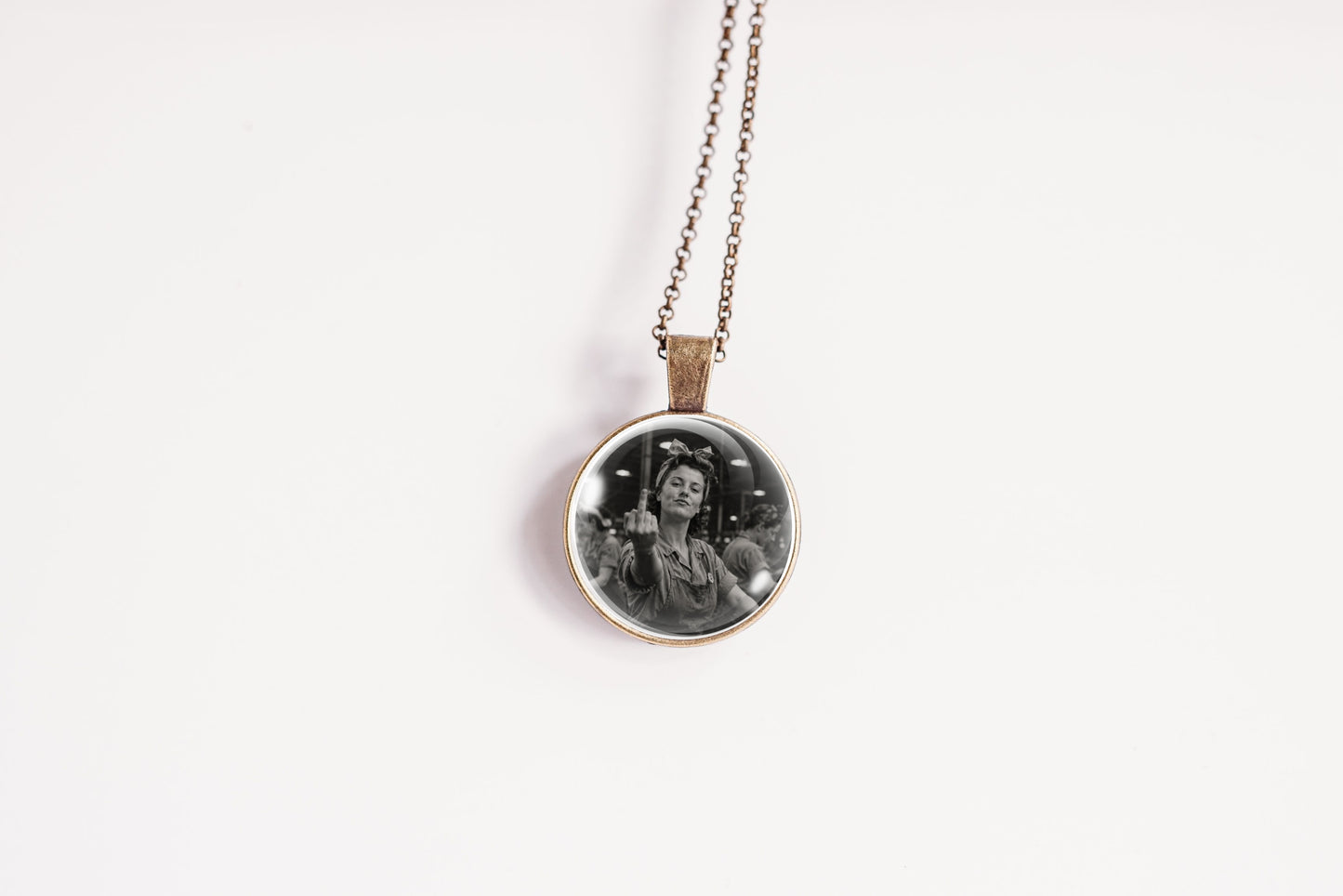 A round pendant necklace featuring a black and white portrait photograph of a woman, suspended from a thin chain on a plain white background.