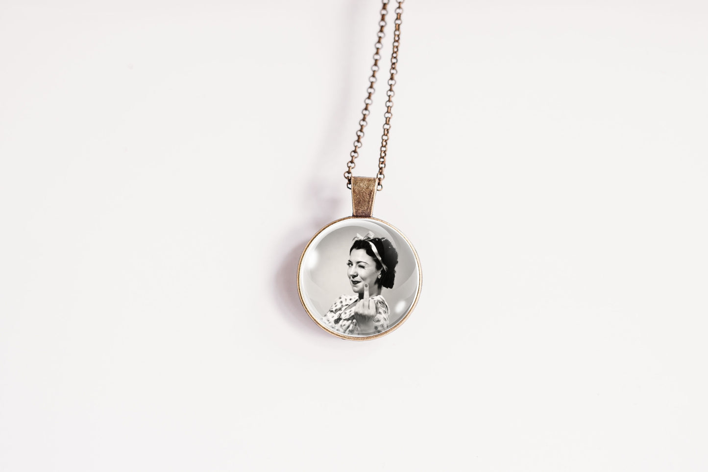 A round pendant necklace featuring a black-and-white portrait photograph of a woman, suspended from a bronze-plated chain against a plain white background.