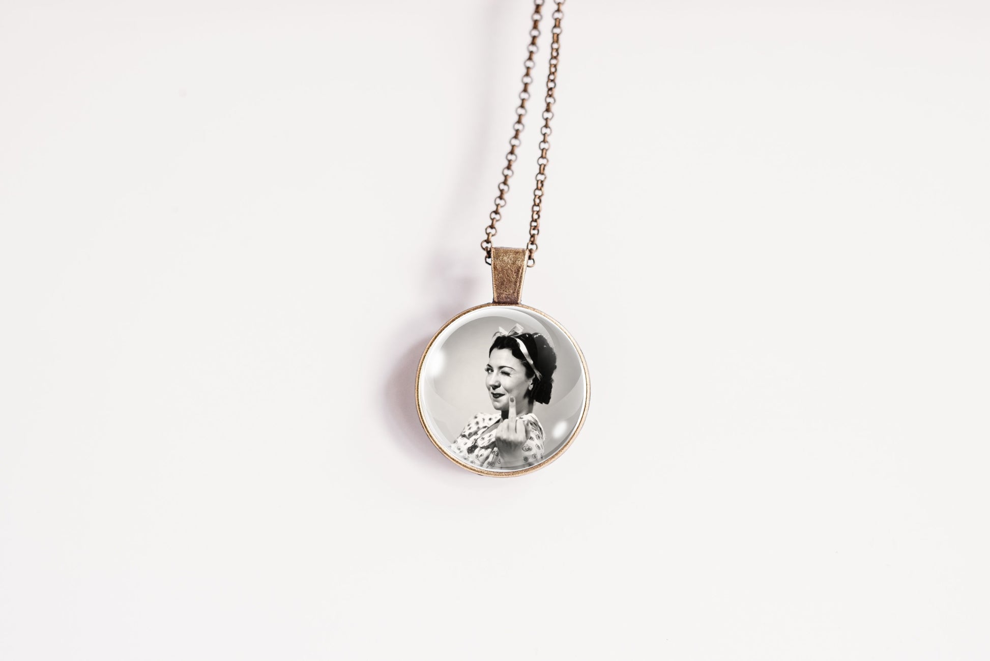 A round pendant necklace featuring a black-and-white portrait photograph of a woman, suspended from a bronze-plated chain against a plain white background.