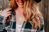 Person wearing a necklace with a floral California poppies pendant, blurred background
