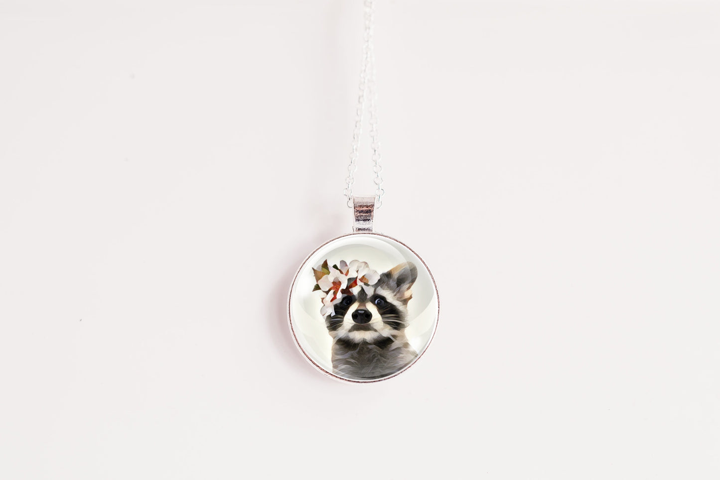 Necklace with a pendant featuring a raccoon wearing a flower crown shown against a white background