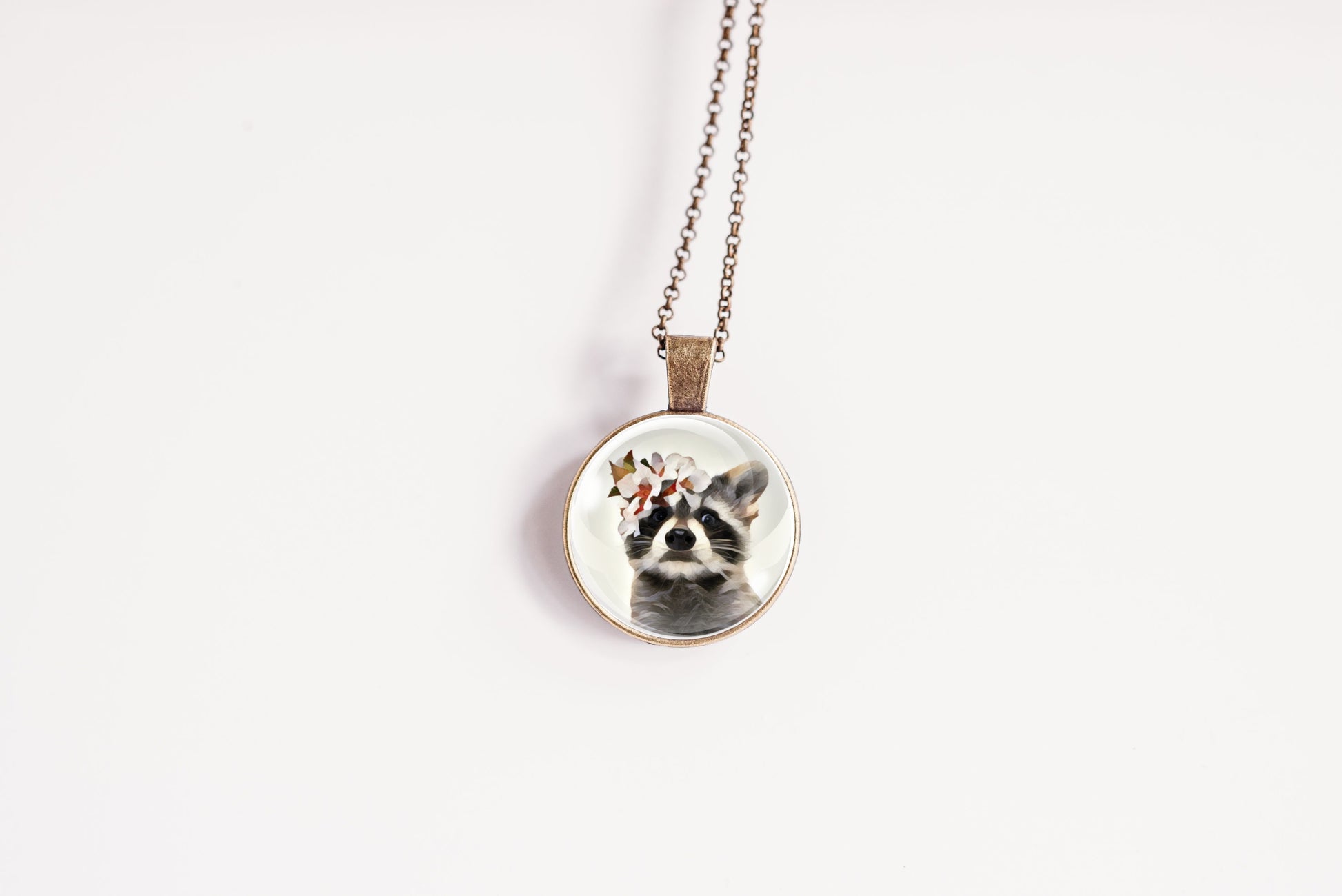Necklace with a pendant featuring a raccoon wearing a flower crown shown against a white background