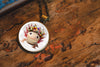 Necklace with a pendant featuring a cute axolotl with flowers on a wooden surface