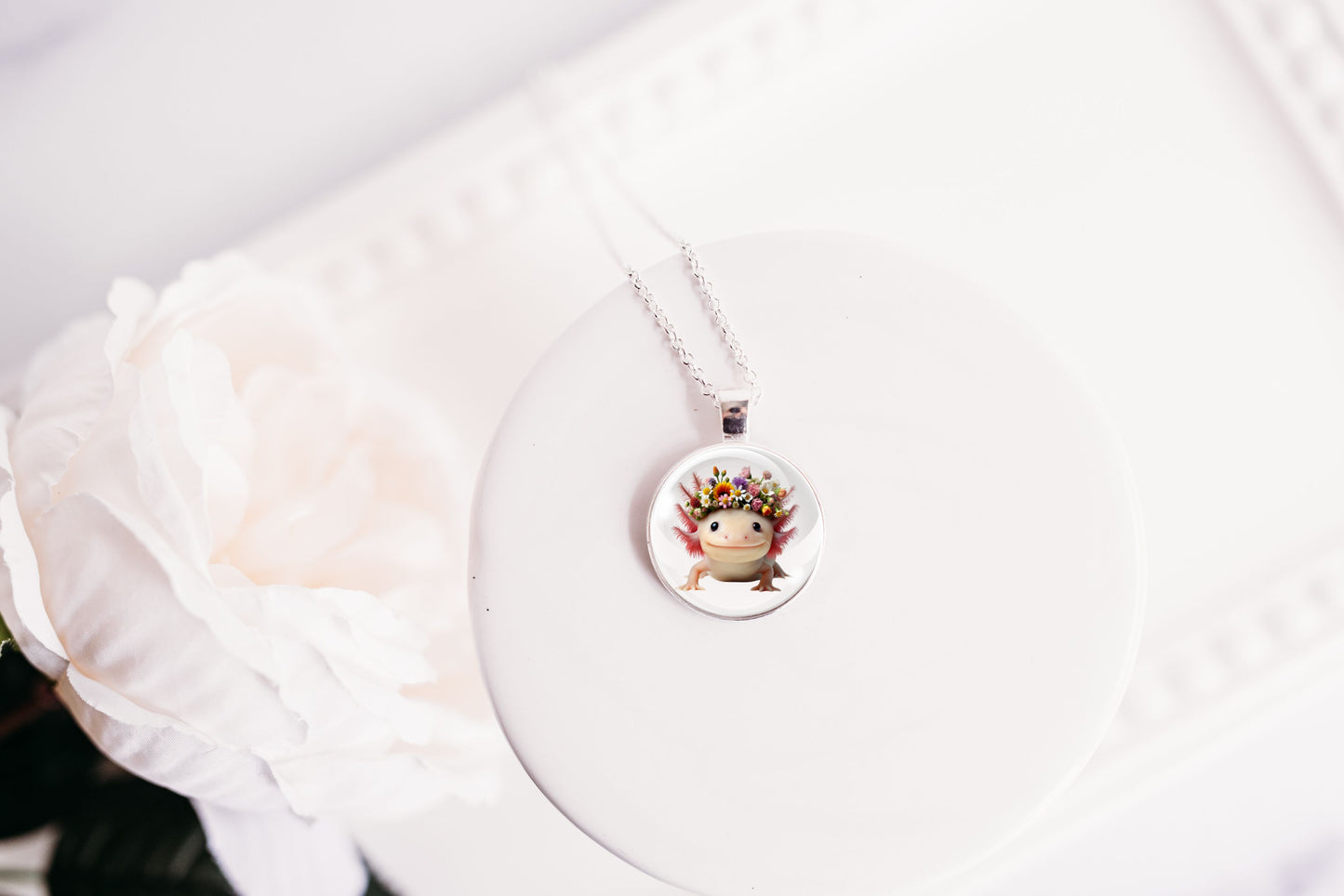 Necklace with a round pendant featuring a cute kawaii axolotl wearing a flower crown on a white background