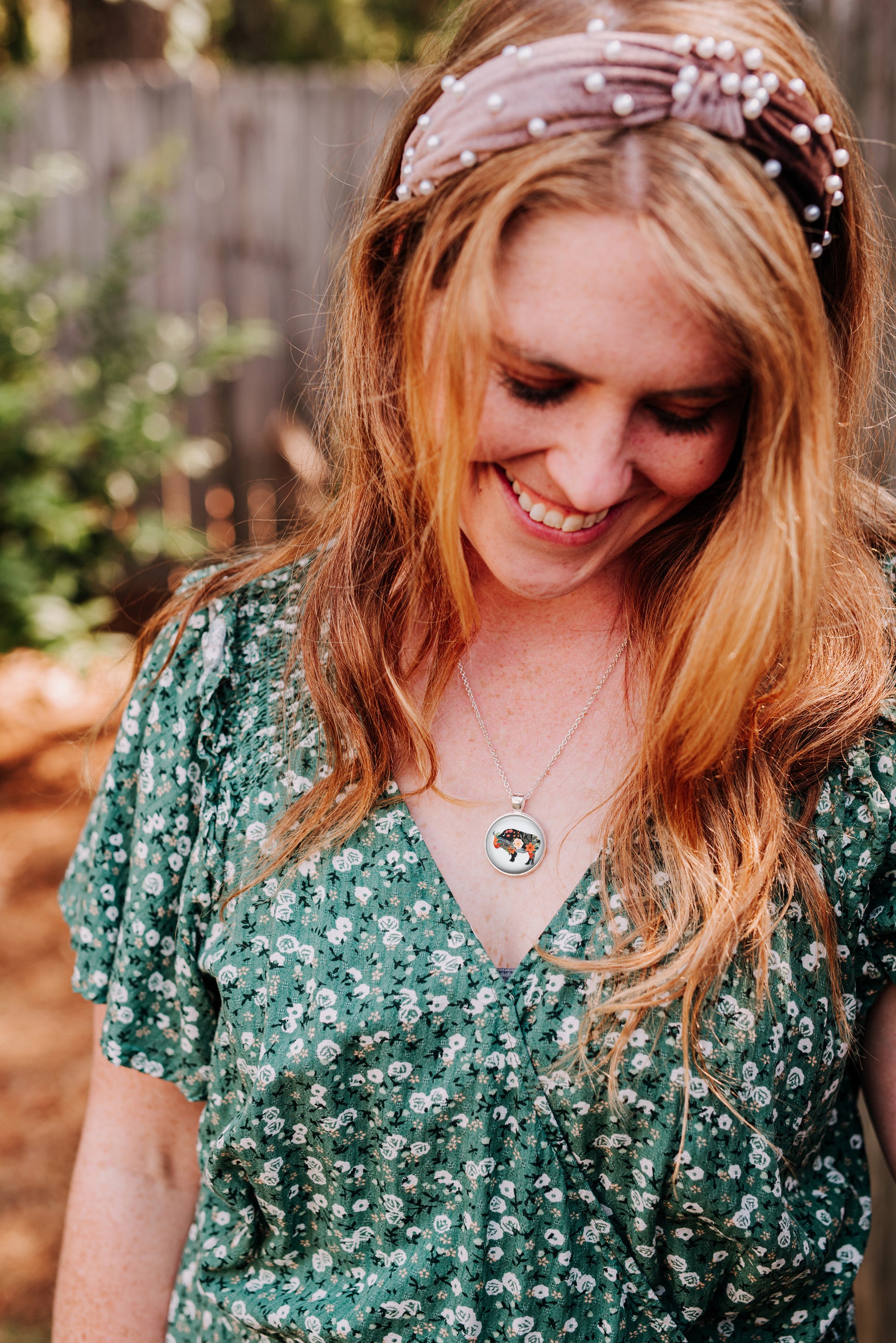 Floral silhouette bison pendant necklace worn by a woman wearing a green floral dress
