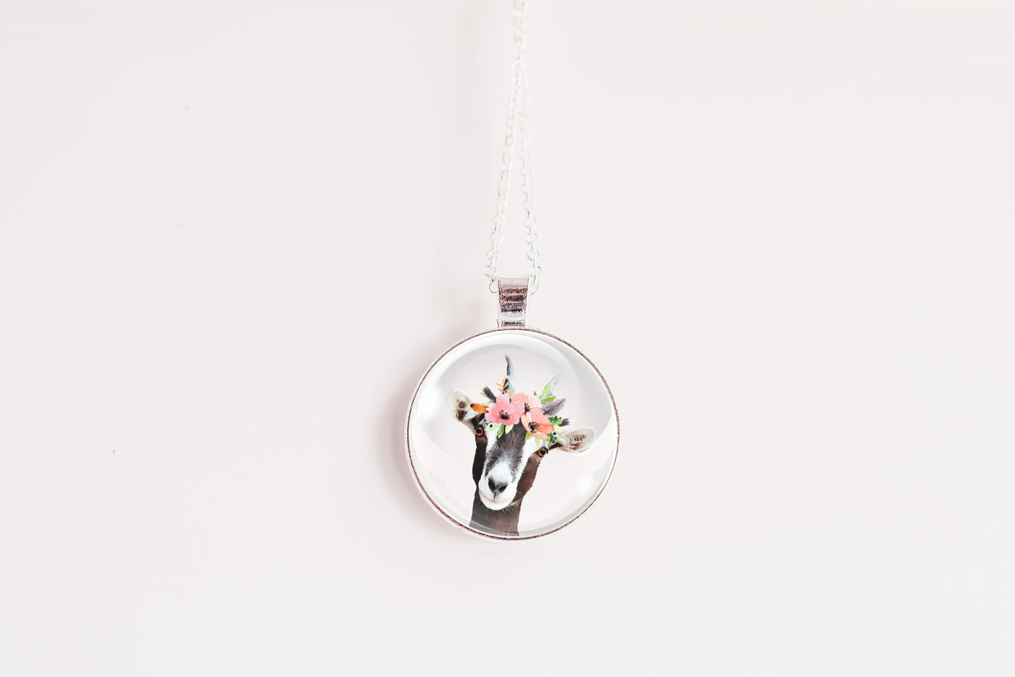 Pendant necklace featuring the image of a goat wearing a flower crown, on a white background