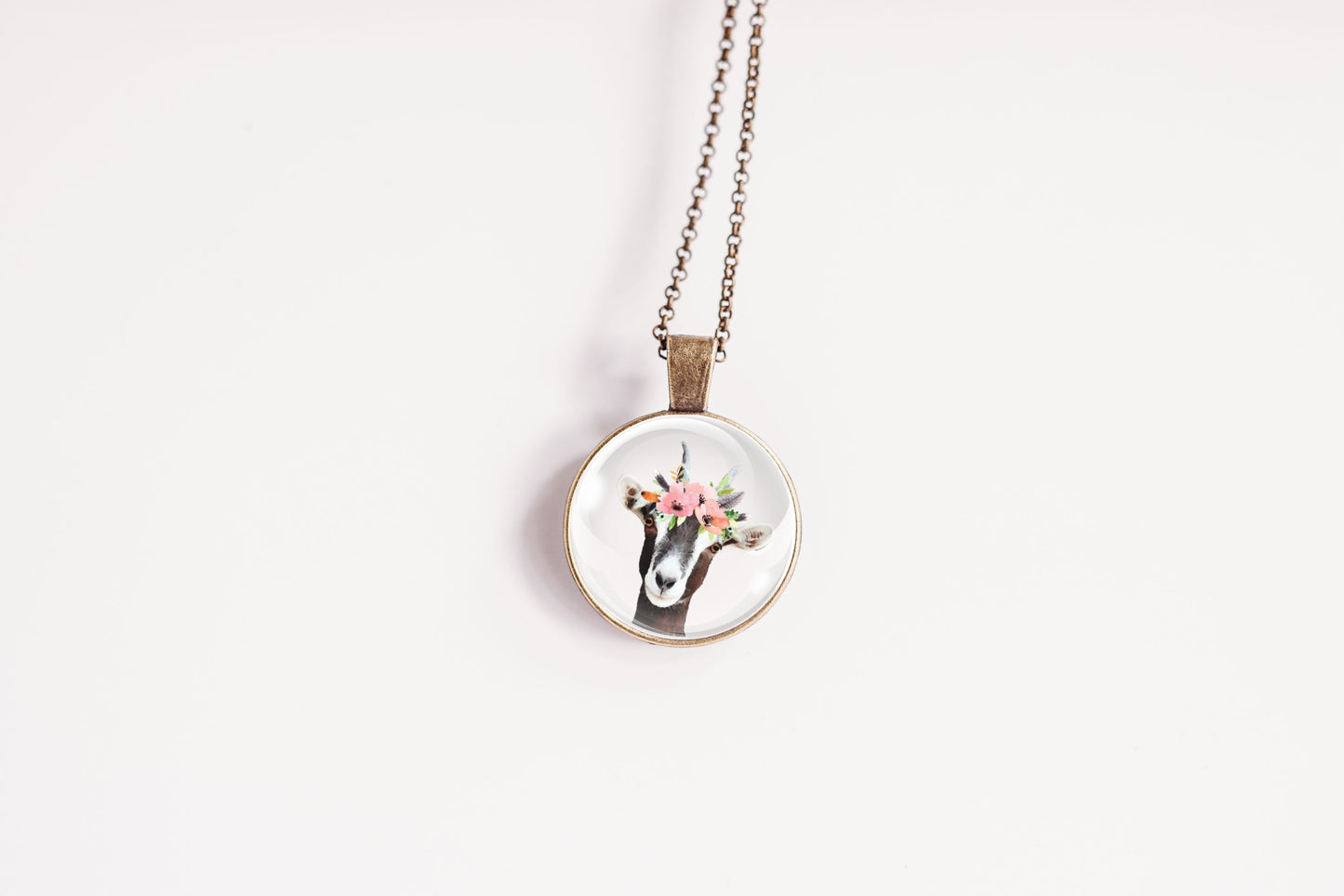 Pendant necklace featuring the image of a goat wearing a flower crown, on a white background