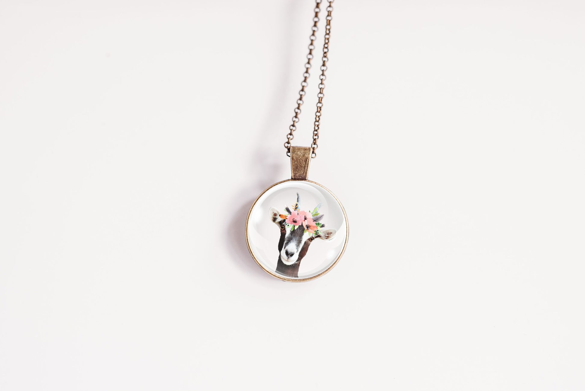 Pendant necklace featuring the image of a goat wearing a flower crown, on a white background