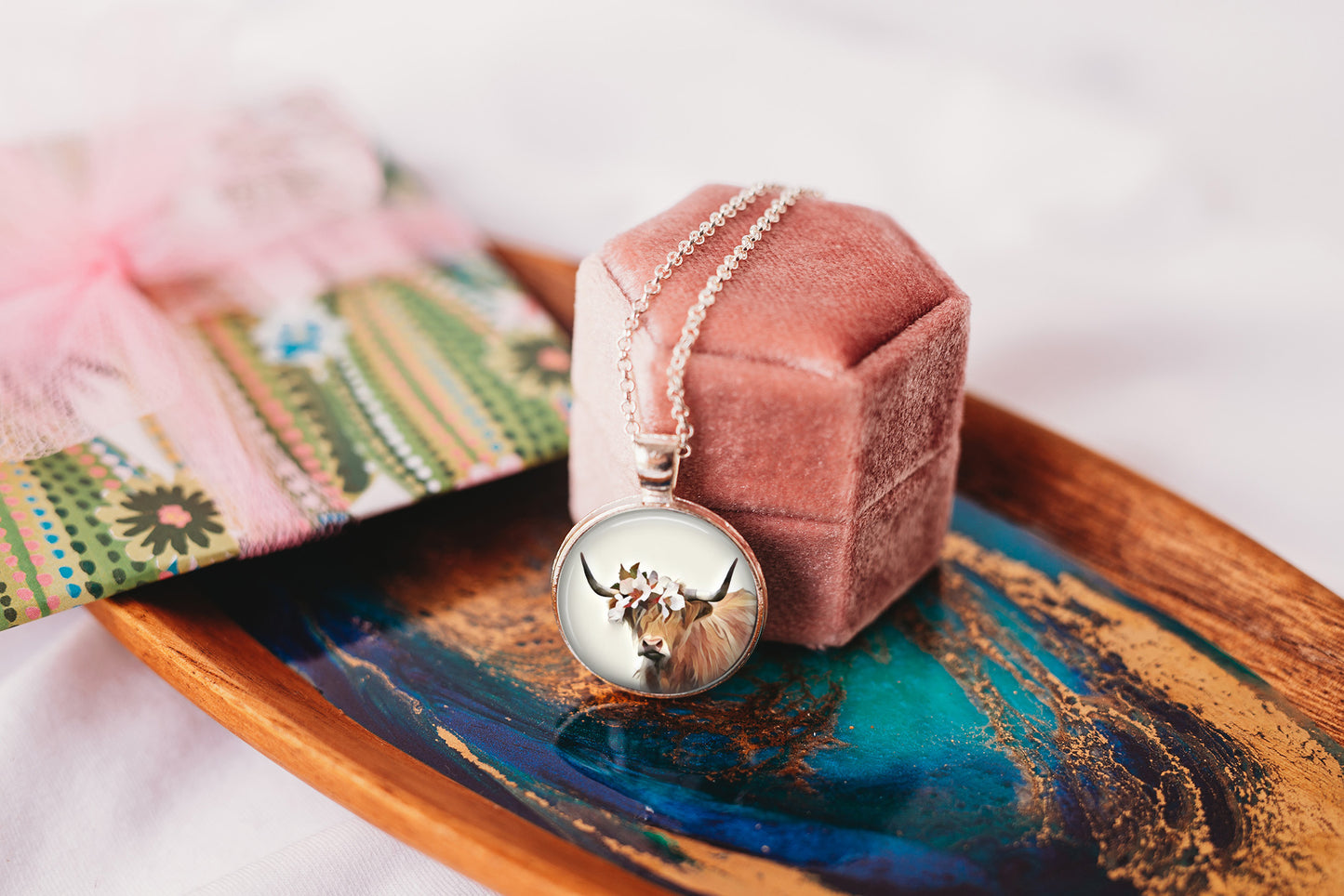 Highland cow pendant necklace with a pendant on a decorative tray