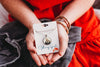 Person holding a necklace with a card labeled 'Whimsy Spirit' against a red garment background