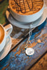 Two coffee cups with a necklace on a wooden surface