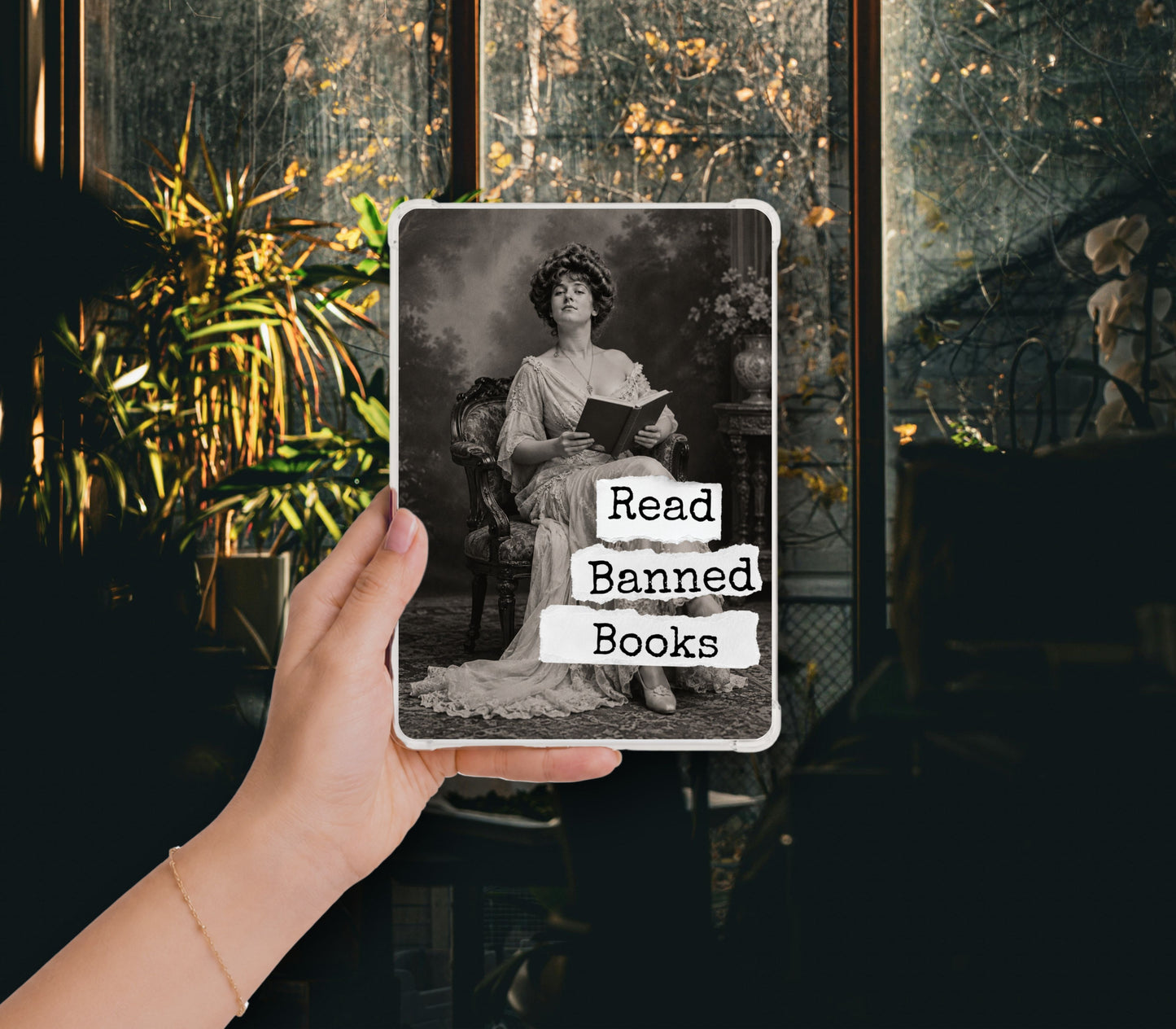Read Banned Books printable Kindle clear case insert featuring an elegantly dressed Victorian woman seated with a book, shown in a clear Kindle case held against a dark botanical background.
