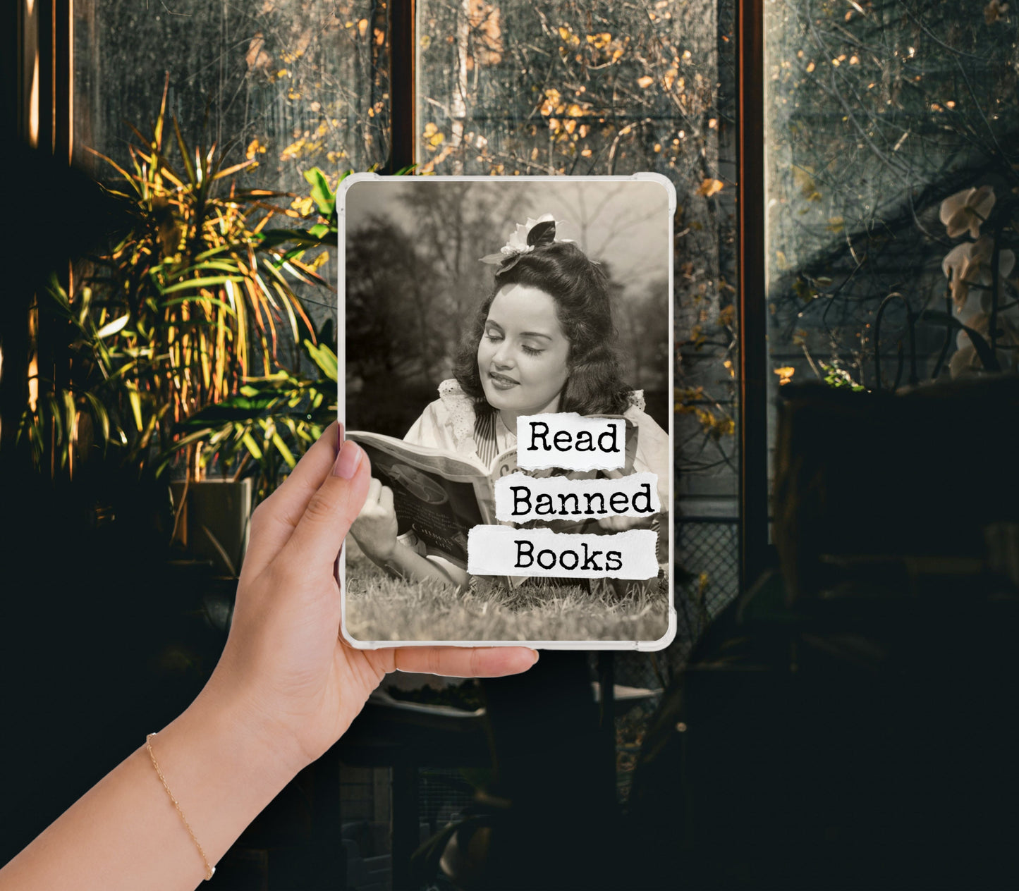 Read Banned Books printable Kindle clear case insert featuring a vintage woman reading outdoors with a curious bird perched above her, shown in a clear Kindle case held against a dark botanical background.