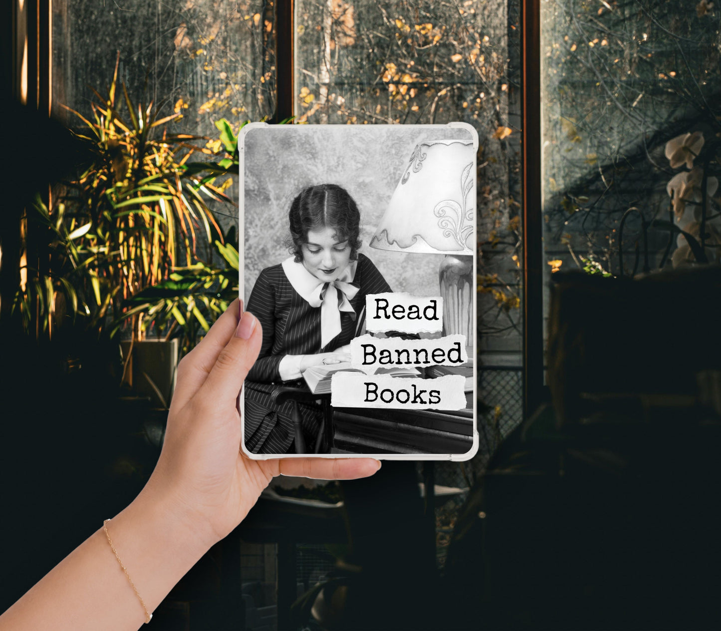 Read Banned Books printable Kindle clear case insert featuring a vintage young woman absorbed in her book, shown in a clear Kindle case held against a dark botanical background.