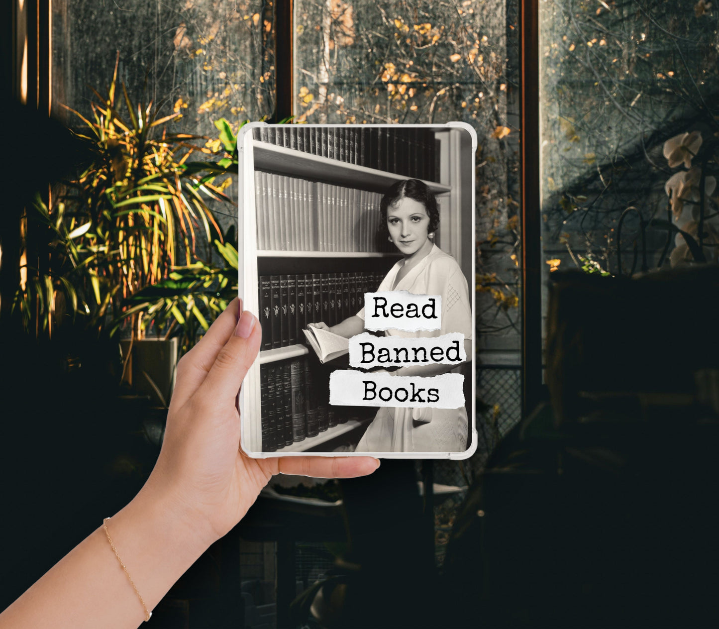 Read Banned Books printable Kindle clear case insert featuring a stylish woman reading among tall library shelves, shown in a clear Kindle case held against a dark botanical background.