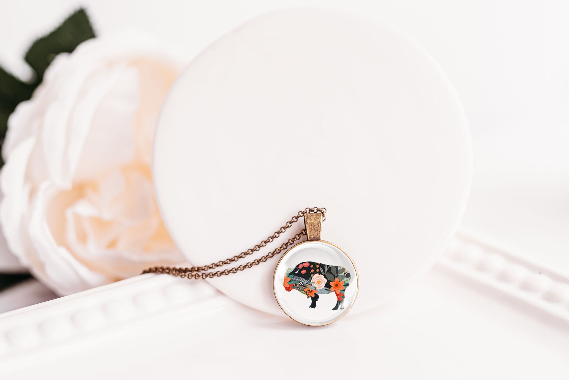 Floral silhouette bison pendant necklace against a white background