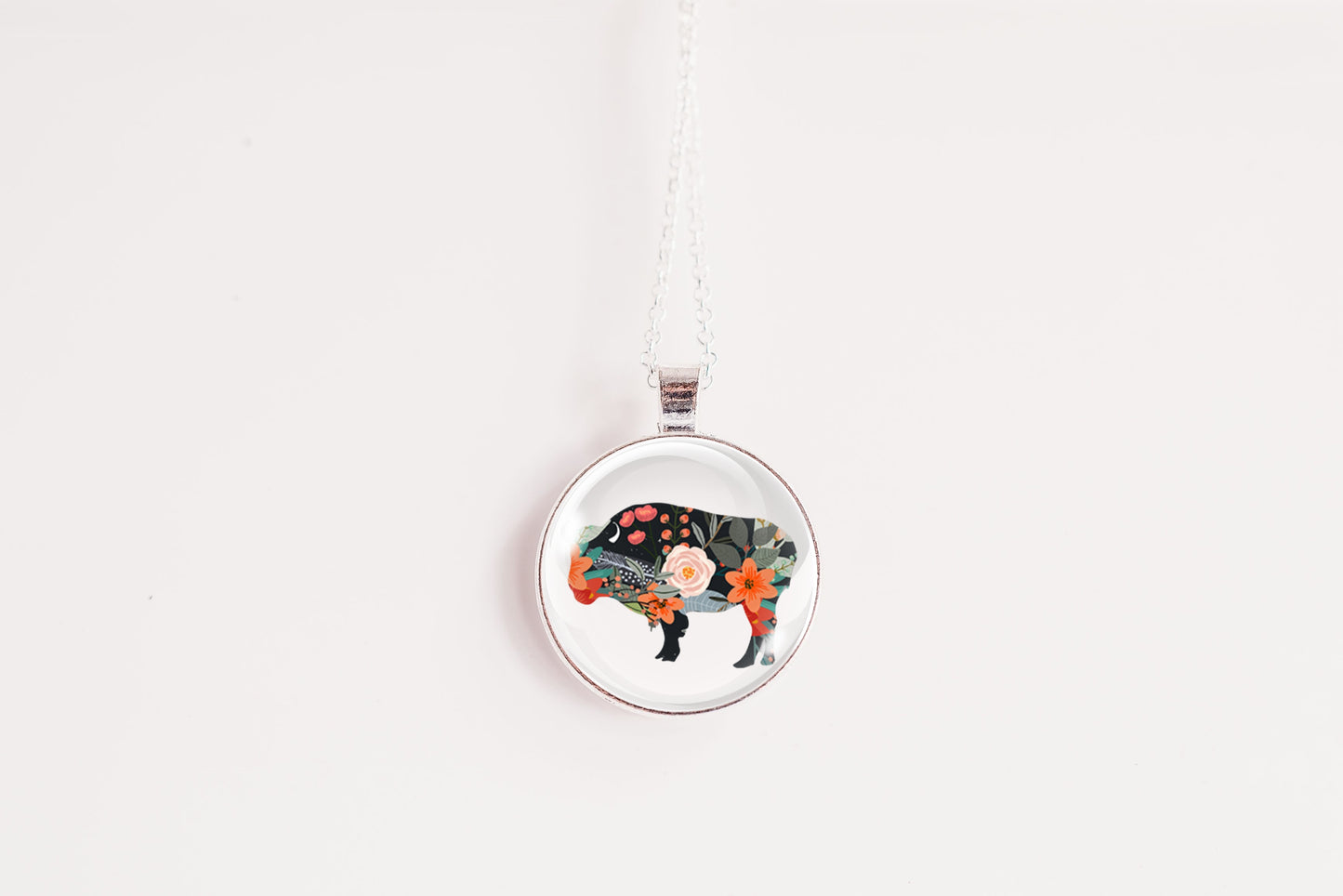 Round pendant with a floral bison design on a white background