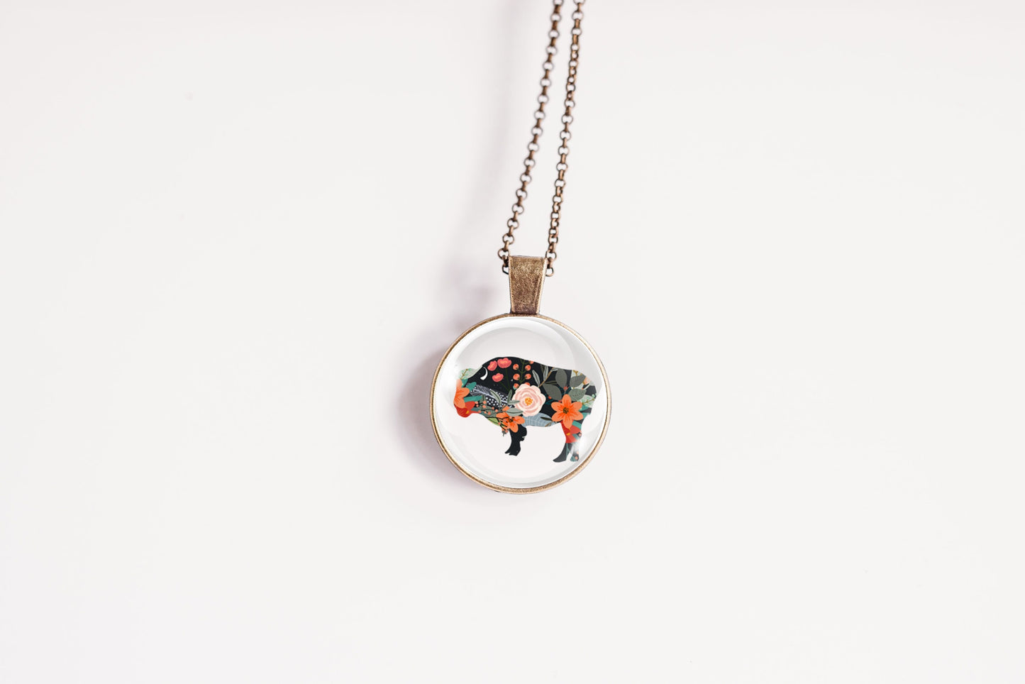 Necklace with a round pendant featuring a floral bison on a white background