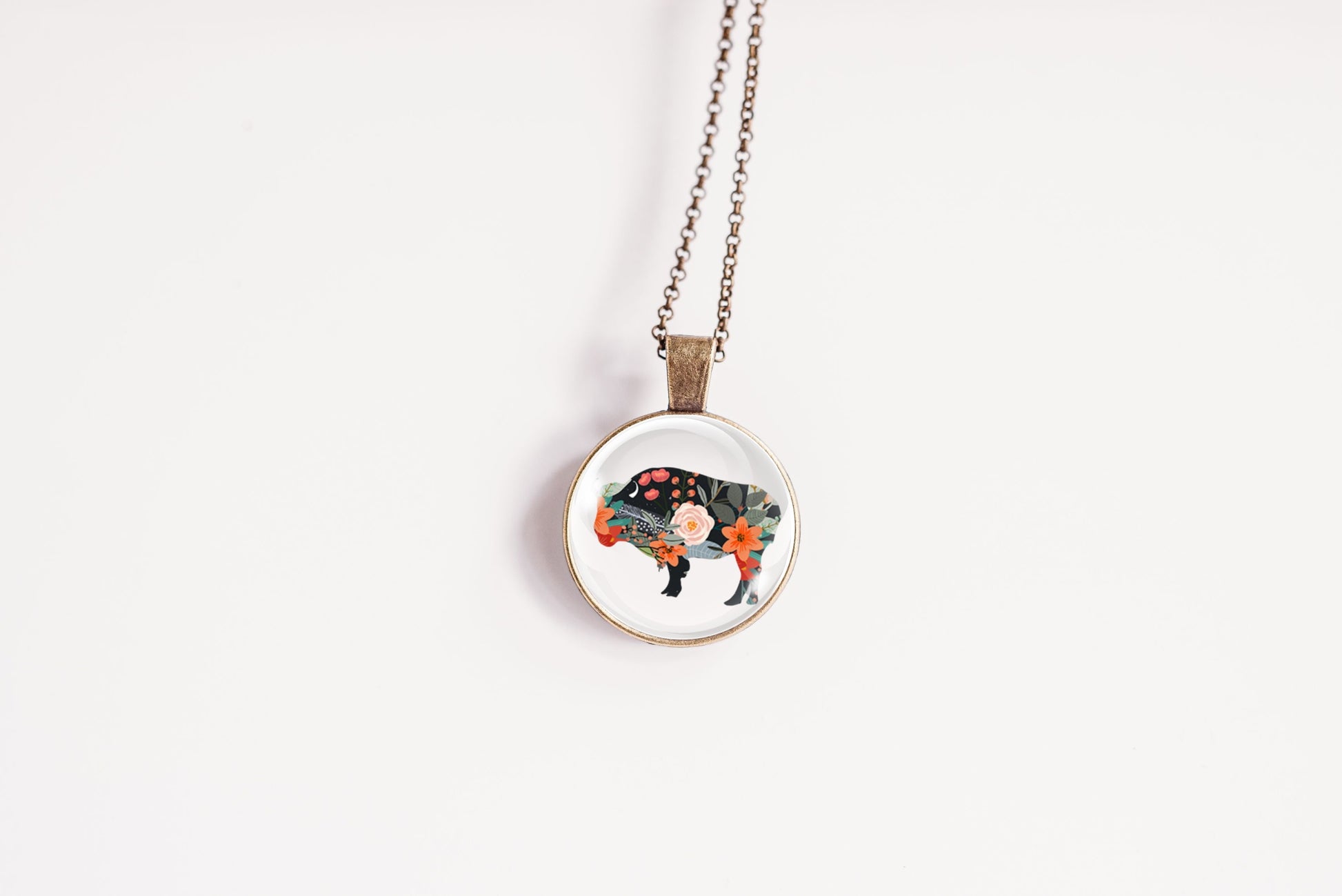 Necklace with a round pendant featuring a floral bison on a white background