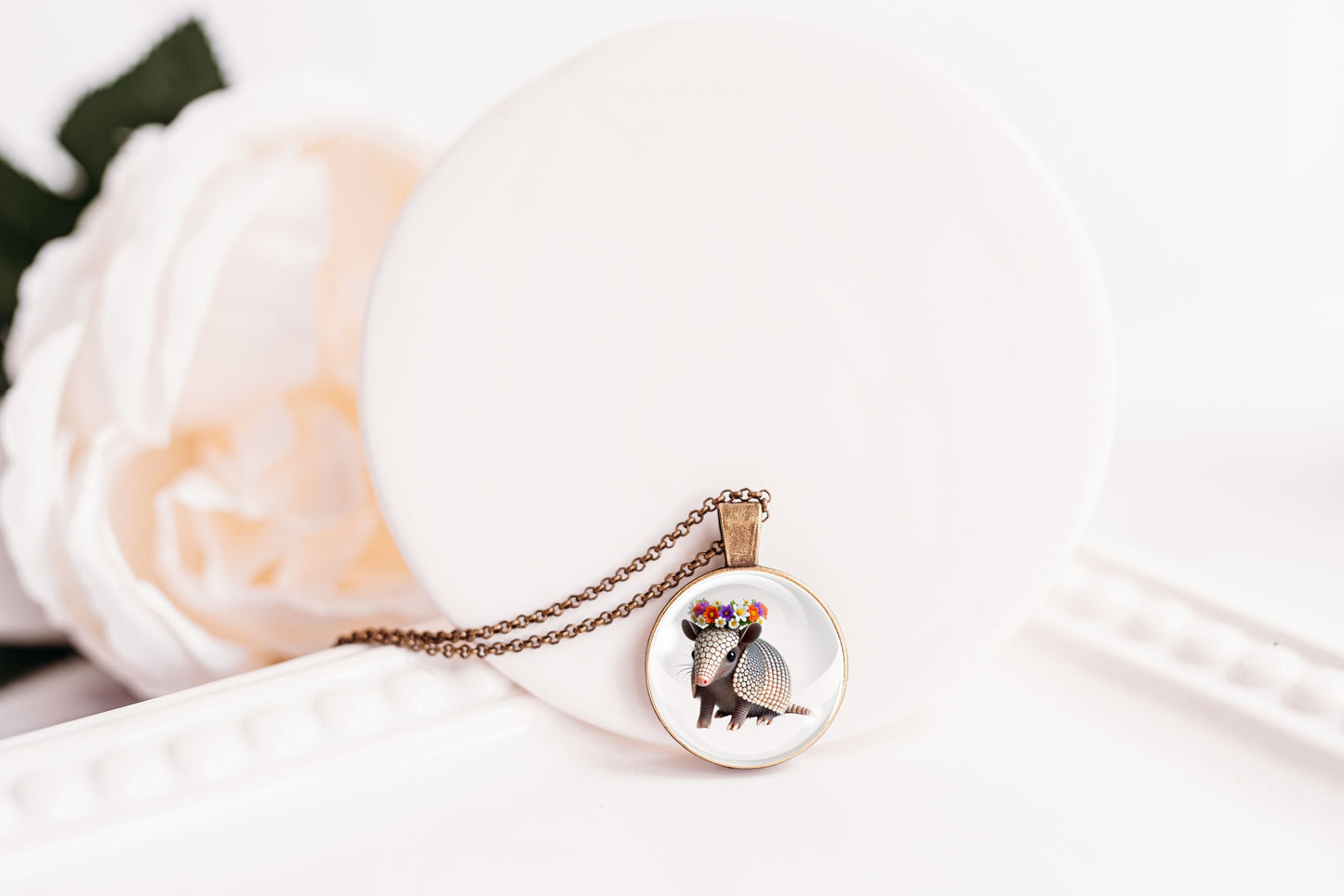 Necklace with a round pendant featuring an image of an armadillo on a white surface.