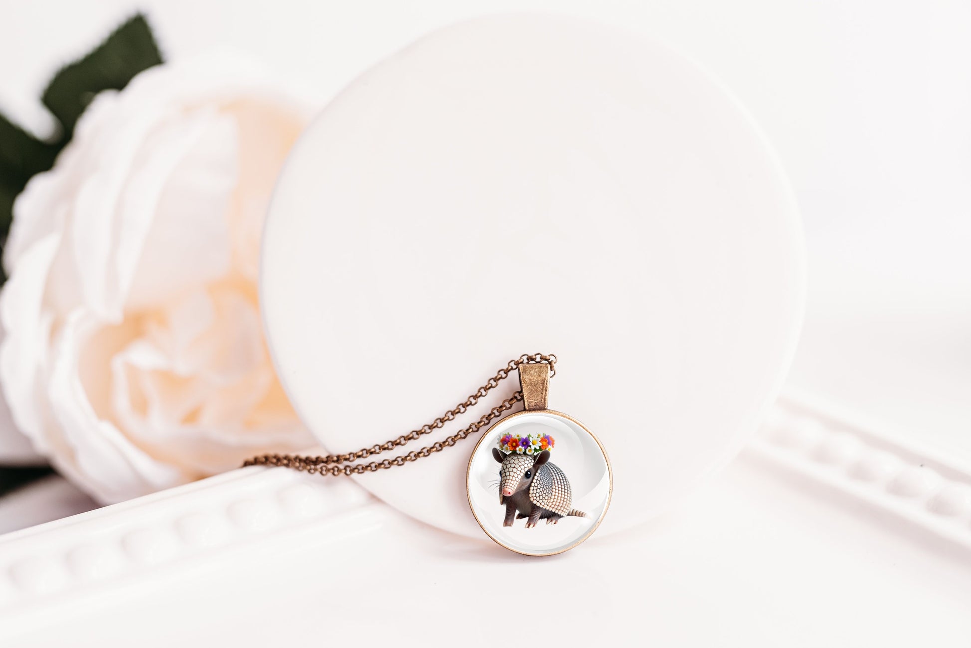 Necklace with a round pendant featuring an image of an armadillo on a white surface.