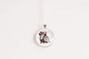 Round pendant with armadillo design and floral headband on a white background