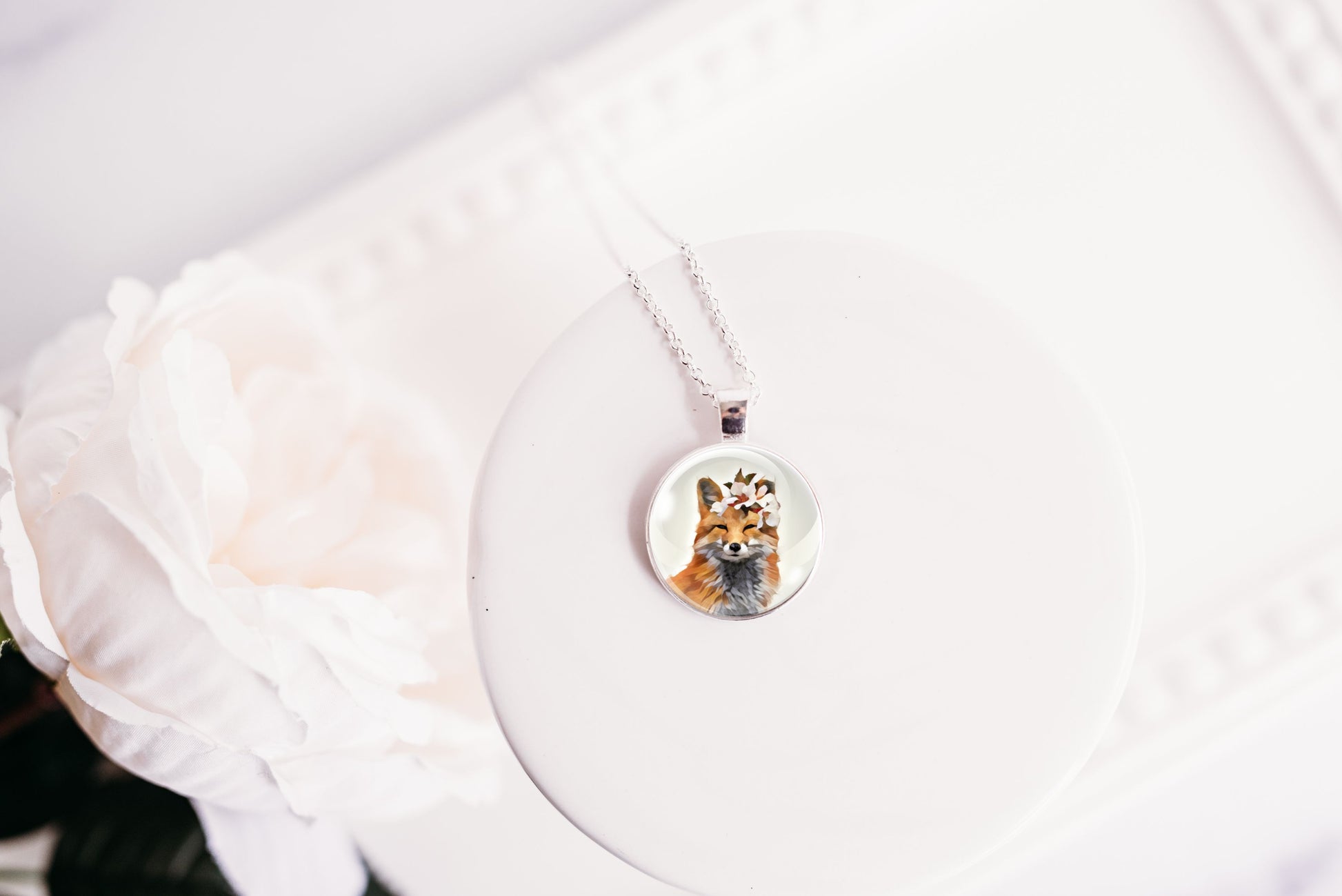 Pendant necklace featuring an image of a fox wearing a flower crown shown against a white background