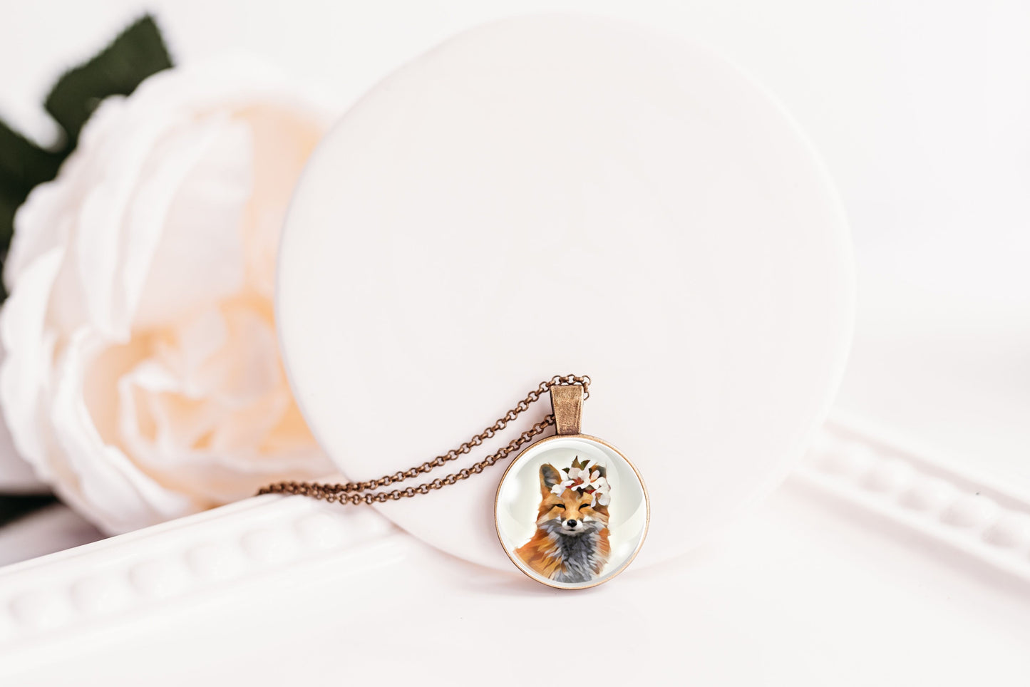 Pendant necklace featuring an image of a fox wearing a flower crown shown against a white background