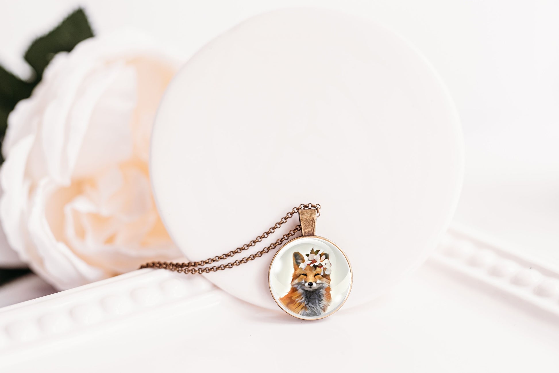 Pendant necklace featuring an image of a fox wearing a flower crown shown against a white background
