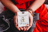 Person holding a giraffe necklace packaging with 'Whimsy Spirit' branding.