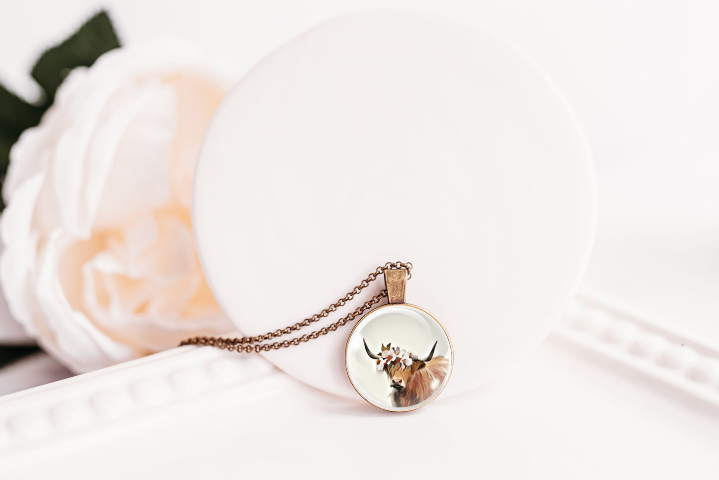 Necklace with a pendant featuring a highland cow design on a white surface.