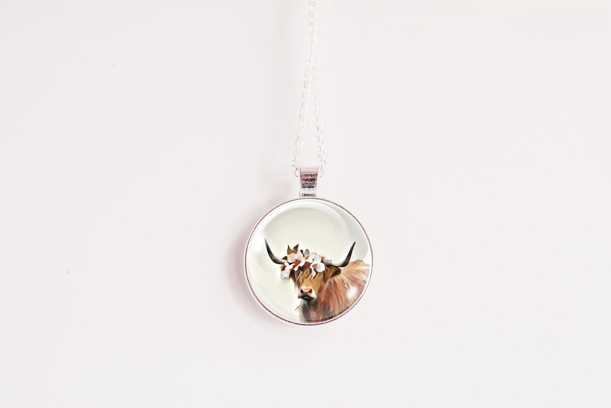 Round pendant with a highland cow design on a white background