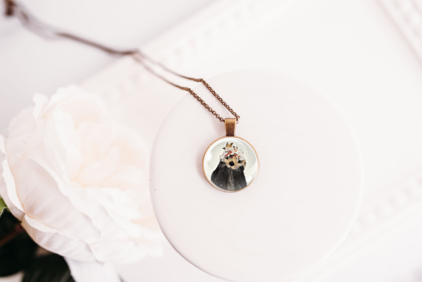 Necklace with a circular pendant featuring an image of a sea otter wearing a flower crown on a white background.
